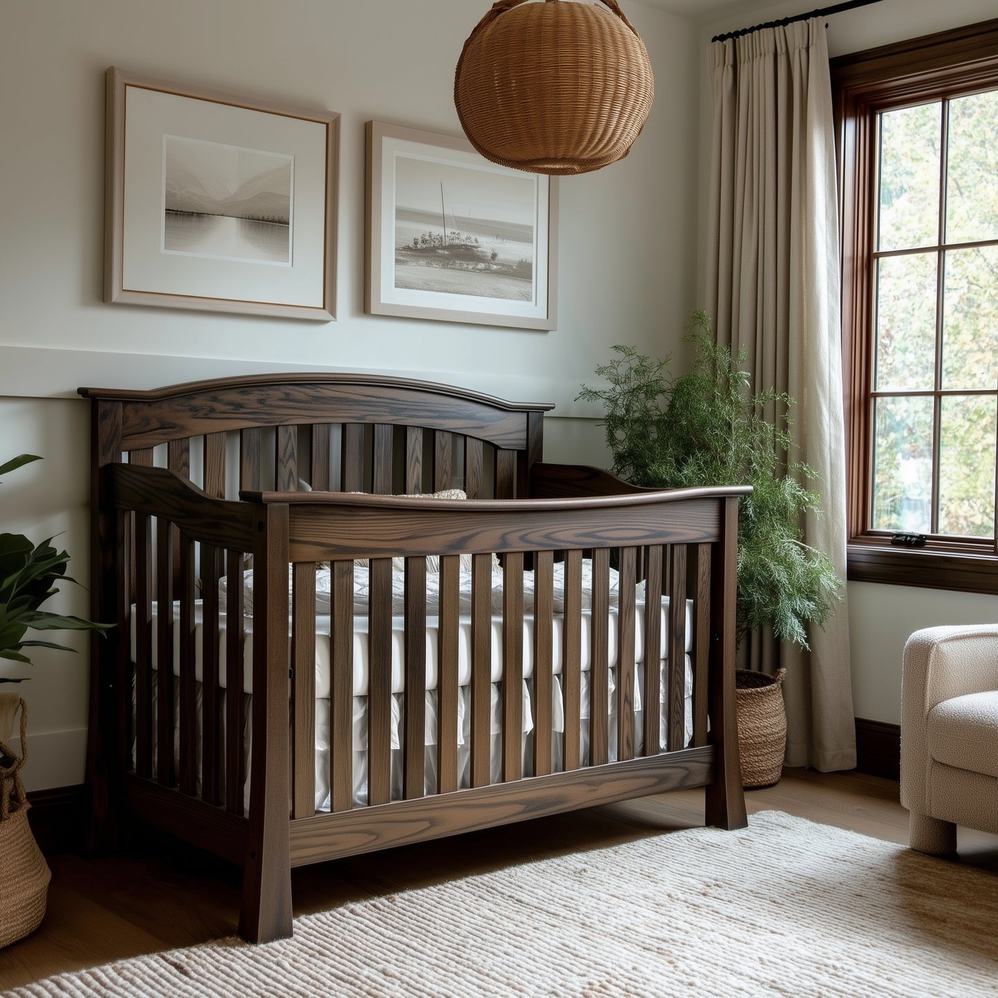 The Archer Crib, featuring slatted wooden sides, stands in a cozy, light-filled nursery with neutral walls, framed art, a potted plant, woven lamp, beige rug, and cream curtains on the window.