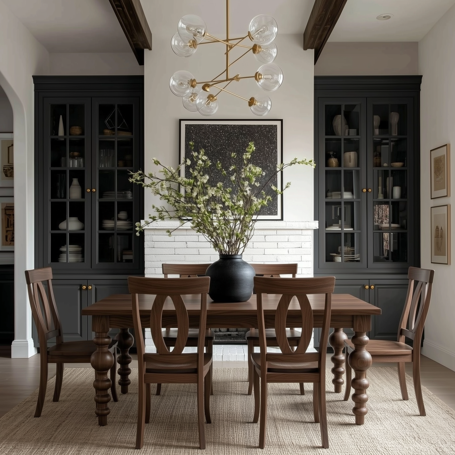 Dining room with wooden table and chairs, black vase with greenery, and dark cabinets. Modern bold turned legs, solid handcrafted usa made walnut dining table and matching chairs customized extendable. organic modern, large dark blue build-ins and white brick fireplace.