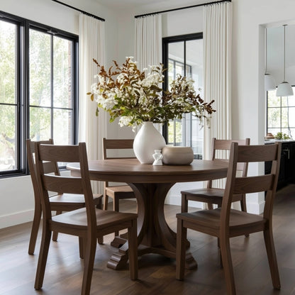 Dining room with walnut handcrafted custom hardwood usa made wooden table and chairs, white vase with flowers, and large windows. black window frames, white drapes
