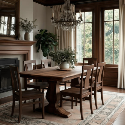 A dining room features The Campbell Dining Table—solid walnut with extension leaves—accompanied by six matching chairs, a patterned rug, chandelier, large windows with cream curtains, fireplace, and green plants. Handcrafted in the USA.