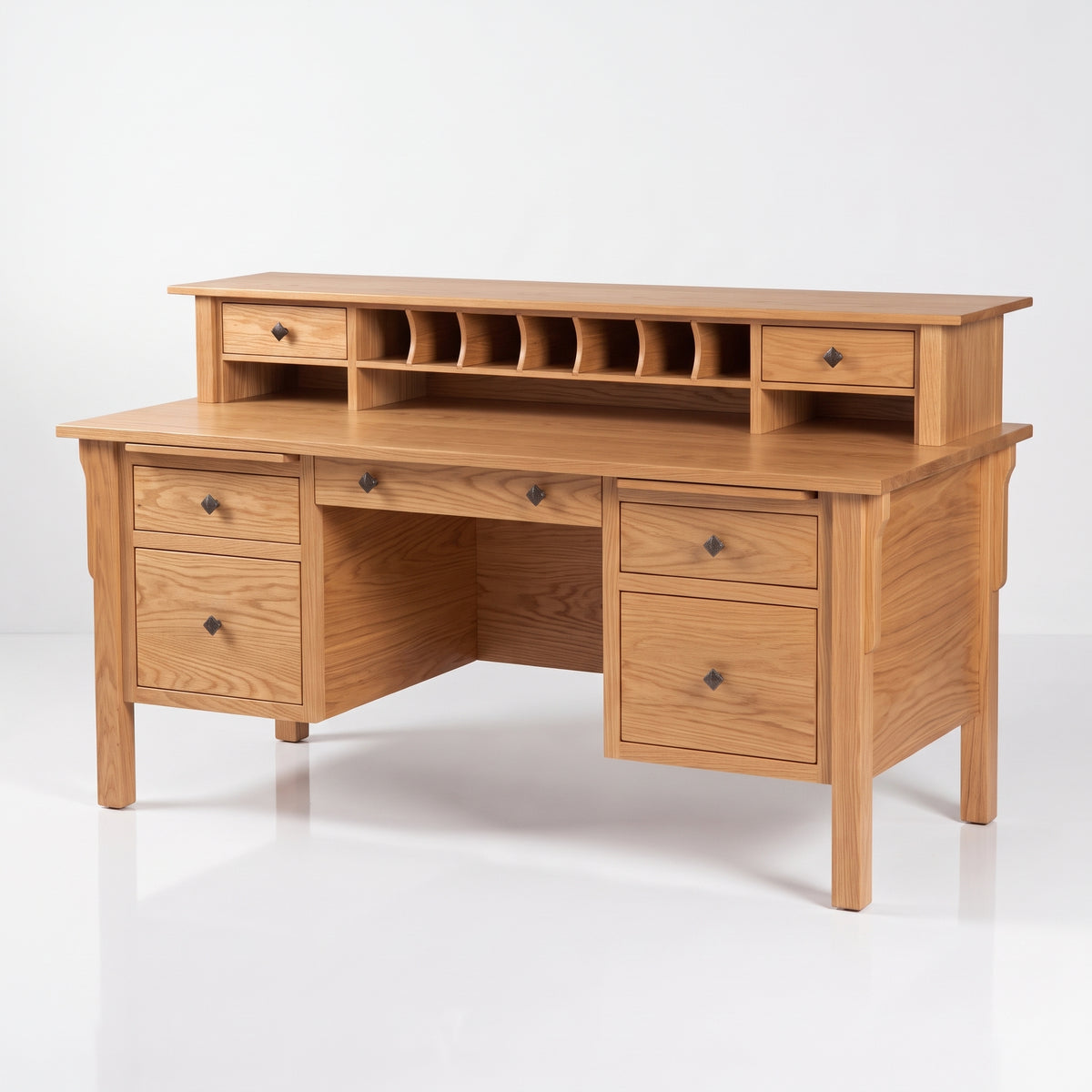 A light oak wood writing desk with a matching dreyfusette hutch, featuring multiple drawers, open cubbies, and dark metal knobs, set against a clean white studio background.