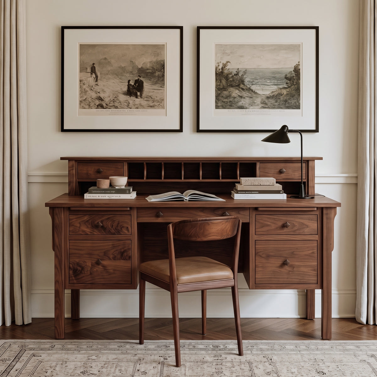 A dark wood writing desk with a hutch and matching wooden chair, styled in a warm, neutral-toned room with two framed landscape prints on the wall above.