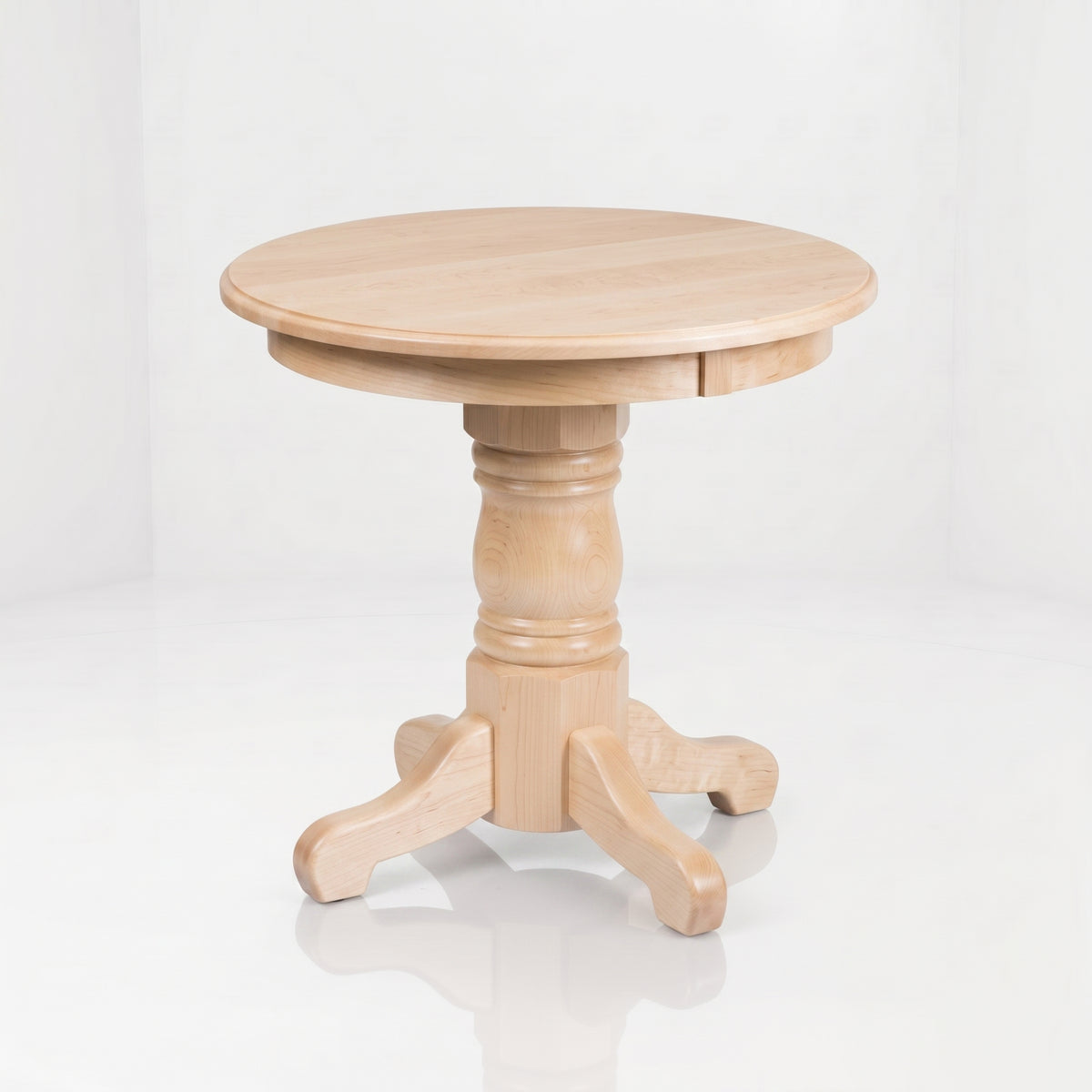 The Colt Round End Table is a round, light wood table with a thick pedestal base and four curved legs, expertly handcrafted of solid wood by American craftsmen. It features a durable top coat and is set against a plain white background.