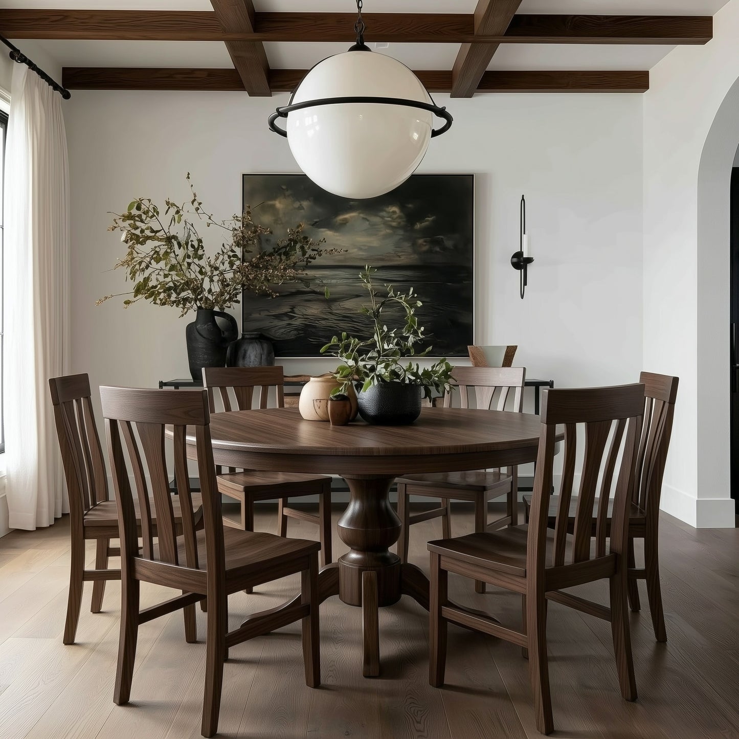 Dining room with wooden walnut usa made custom hardwood table and chairs, large round pendant light, and wall art. Modern organic with moody panting, walnut box beams. white draped