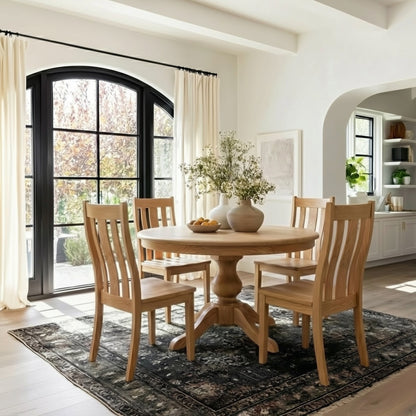 Dining room with wooden table and chairs in a bright room with large windows.