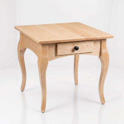 Expertly handcrafted in the USA, The Fox End Table is a light solid wood square side table featuring elegant curved legs and a single front drawer with a round black knob, all showcased against a plain white background.