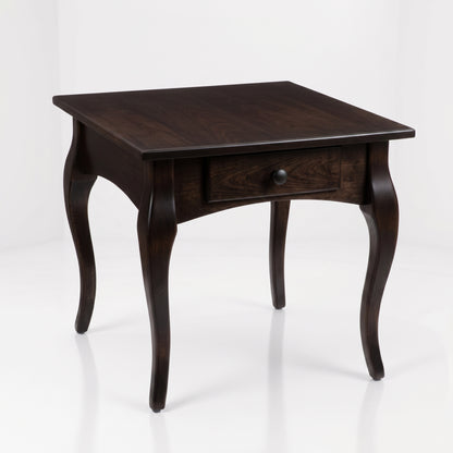 The Fox End Table, handcrafted by American artisans from solid dark wood, features elegant curved legs and a single front drawer with a round knob, and is photographed against a plain white background.