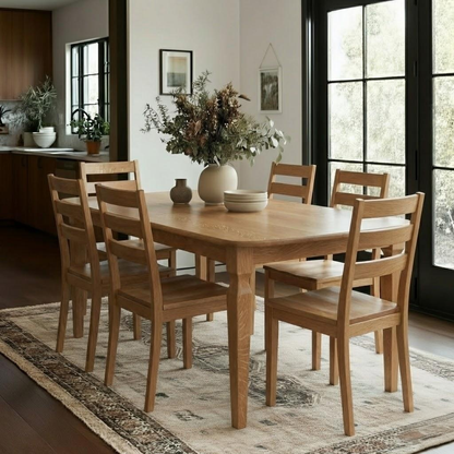 Wooden dining table with chairs in a room with large windows.