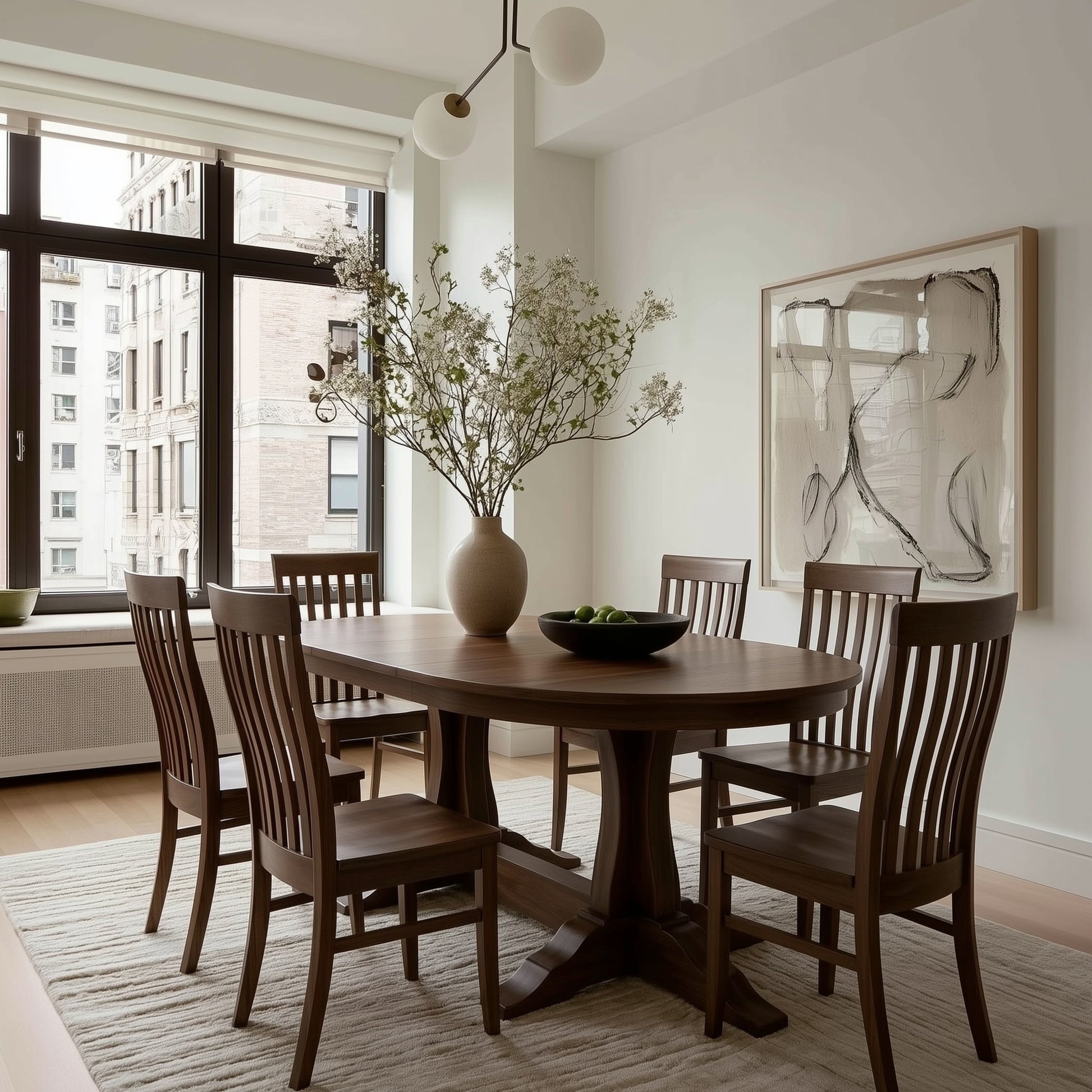 handcrafted custom walnut oval dining table and walnut usa made chairs in a city living room with big black frame window, modern art, natural rug. Organic modern feel