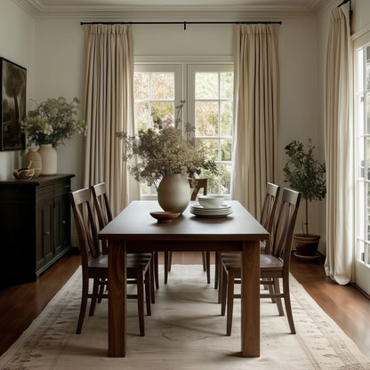 handcrafted american made walnut Dining room table with wooden walnut chairs, large windows, and decorative plants.