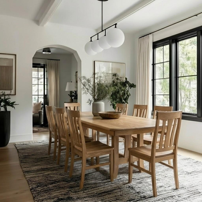 Dining room with wooden table and chairs, large window, and plants.