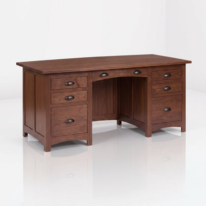 The Owen Hardwood Desk is a dark wood executive piece with two pedestals, five total drawers, two central drawers, and curved metal pulls.