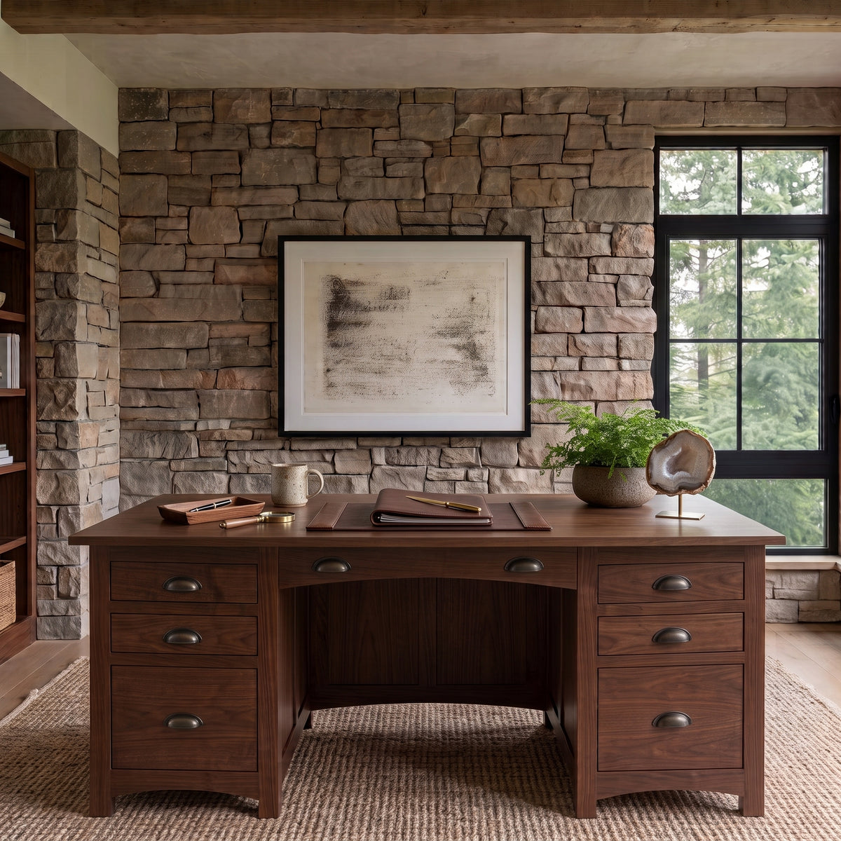 The Owen Hardwood Desk, a solid hardwood executive desk with six drawers and a leather writing pad, positioned against a stone wall.