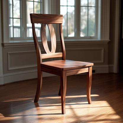 The Sutton Chair, featuring an oval cutout in its backrest, sits in sunlight on a hardwood floor before large windows and cream-colored paneled walls.