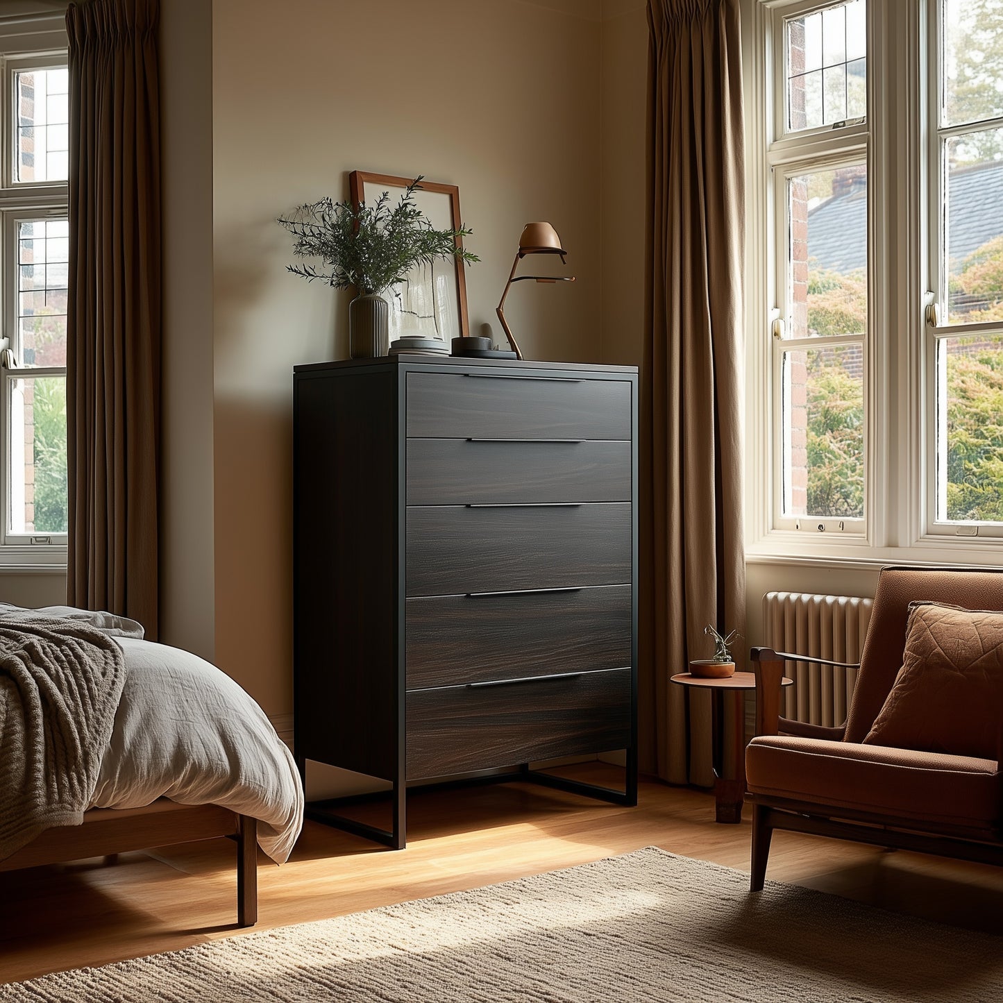 A tidy bedroom corner featuring The Preston Chest of Drawers in dark wood, a small side table with a vase, a brown armchair, and large windows with beige curtains allowing natural light.