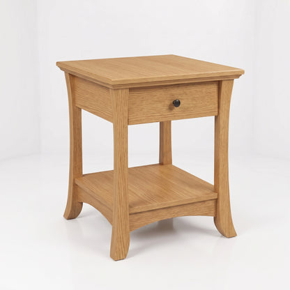 The Veris End Table, handcrafted in the USA from solid wood furniture, features a light wood finish, a single drawer with a black knob, flared legs, and a lower shelf. Finished with a durable top coat and set against a plain white background.